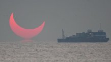 The sun, partially blocked by the moon, rises above the sea in Al Wakrah, Qatar, Dec. 26, 2019. Facebook and Twitter users were quick to draw comparisons between the reddened partial eclipse to "devil horns."