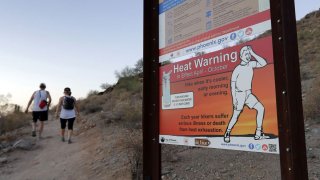 A sign warns hikers about severe heat as they begin their hike at sunrise to avoid the excessive heat, Friday, June 16, 2017, in Phoenix.