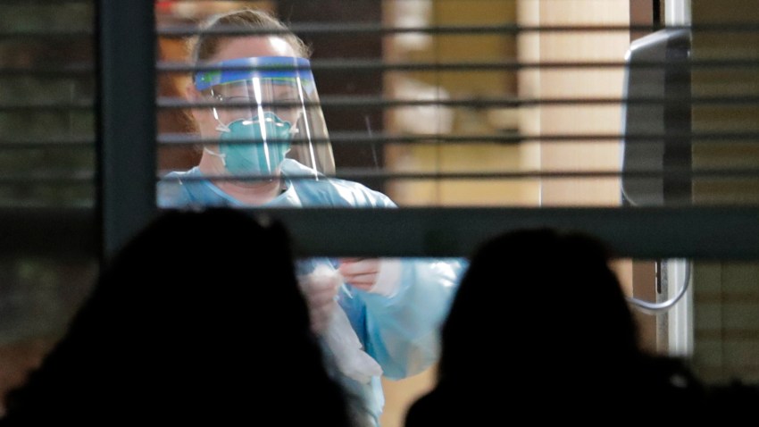A worker wearing protective gear is seen through a window