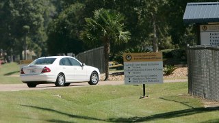 FILE - In this Sept. 26, 2006, file photo a person drive through the gates of a federal prison in Oakdale, La.