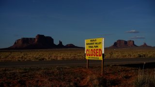 This April 23, 2020 photo shows a sign posted in Oljato-Monument Valley, Utah, saying the Navajo Monument Vally Tribal Park is closed, in an effort to prevent the spread of COVID-19 on the Navajo reservation. The reservation has some of the highest rates of coronavirus in the country.