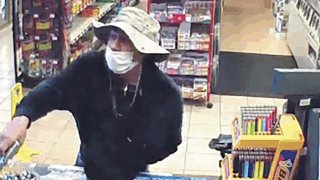 This image from surveillance video shows a man, believed to be William Rosario Lopez wearing a surgical mask, with a gun in a Connecticut convenience store