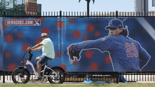 A cyclist rides past Principal Park, home to the Triple-A minor league baseball Iowa Cubs, Thursday, June 25, 2020, in Des Moines, Iowa. Two high school baseball games scheduled for Thursday at the stadium were postponed after officials said a ballpark staff member tested positive for coronavirus.