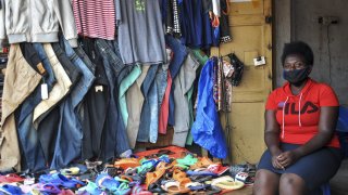 Grace Twisimire, 25, sits in her once-thriving shop selling clothes and plastic shoes in the capital Kampala, Uganda