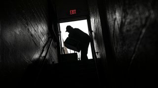 A volunteer is seen in silhouette as he carries cartons of food donations at St. Stephen Outreach in the Brooklyn borough of New York, March 20, 2020.