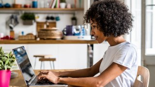 Woman using laptop at table at home