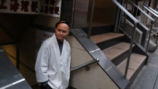 a restaurant worker stands in the street in New York's Chinatown in New York City