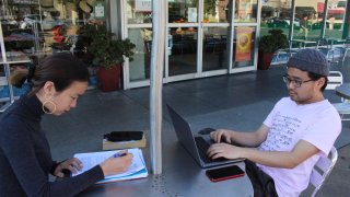 International students Yaqing "Victoria" Yang and Ende Shen of China study together at a sidewalk table in the Silicon Valley city of Palo Alto