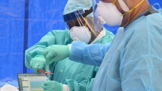 In this May 8, 2020, file photo, healthcare workers place a nasal swab from a patient into a tube for testing at the Brightpoint Health and UJA-Federation of New York free pop-up coronavirus (COVID-19) testing site in the Brooklyn borough of New York City.