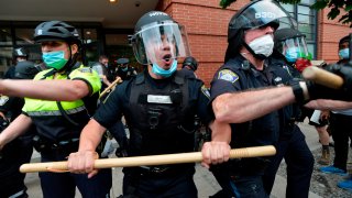 Police officers hold batons as they clash with protestors against police brutality and racism in the US, with the recent deaths of George Floyd, Ahmaud Arbery, Breonna Taylor, in Boston, Massachusetts, on May 29, 2020. – The Minneapolis police officer accused of killing George Floyd, a handcuffed African American man, was charged with murder on May 29 as authorities declared a curfew after three nights of violent protests left parts of the city in flames. (Photo by Joseph Prezioso / AFP) (Photo by JOSEPH PREZIOSO/AFP via Getty Images)