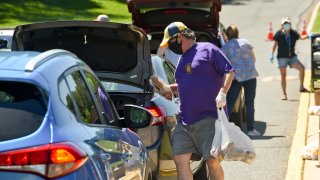 Cumru, PA - May 30: Todd Kaley, with the Shillington Lions Club carries food to a car. During a food distribution by the Wyomissing Restaurant and Bakery, Olivet Boys and Girls Club, Kuhn Funeral Homes and Shillington Lions Club, at the Gov. Mifflin Intermediate School in Cumru Saturday morning May 30, 2020 during the coronavirus / COVID-19 outbreak. People lined up in cars, but they also gave food to people who walked up. (