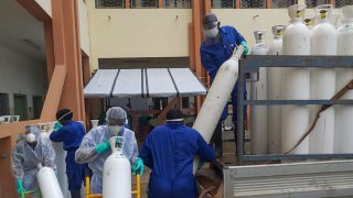 In this May 20, 2020, file photo, medical workers offload cylinders of oxygen at the Donka public hospital where coronavirus patients are treated in Conakry, Guinea. Before the coronavirus crisis, the hospital in the capital was going through 20 oxygen cylinders a day. By May, the hospital was at 40 a day and rising, according to Dr. Billy Sivahera of the aid group Alliance for International Medical Action.