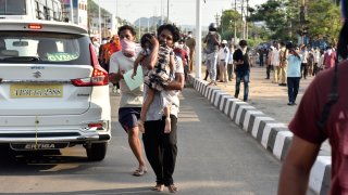 A man runs carrying a child affected by a chemical gas leak in Vishakhapatnam, India, Thursday, May 7, 2020. Chemical gas leaked from an industrial plant in southern India early Thursday, leaving people struggling to breathe and collapsing in the streets as they tried to flee.