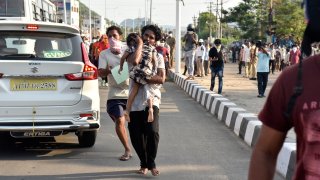 A man runs carrying a child affected by a chemical gas leak in Vishakhapatnam, India, Thursday, May 7, 2020. Chemical gas leaked from an industrial plant in southern India early Thursday, leaving people struggling to breathe and collapsing in the streets as they tried to flee.