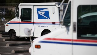 U.S. Postal Service mail vehicles sit in a parking lot at a mail distribution center