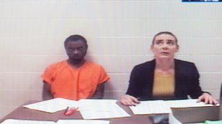 In this Sept. 13, 2019, file photo, Tevin Biles-Thomas, left, shown on a video monitor, listens to his arraignment with public defender Alonda Bush from the Cuyahoga County jail as the hearing is held in Common Pleas Court in Cleveland. Biles-Thomas is accused of killing three people at a New Year's Eve party in 2018 and is the older brother of U.S. Olympic gymnast Simone Biles.