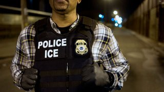 A U.S. Immigration and Customs Enforcement (ICE) agent waits as a group of undocumented men, not pictured, are deported to Mexico at the U.S.-Mexico border in San Diego, California, U.S., on Thursday, Feb. 26, 2015.