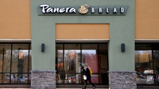 In this Wednesday, April 12, 2017, file photo, a passer-by walks near an entrance to a Panera Bread restaurant in Natick, Mass.
