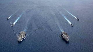 In this photo provided by U.S. Navy, the USS Ronald Reagan (CVN 76) and USS Nimitz (CVN 68) Carrier Strike Groups steam in formation, in the South China Sea, July 6, 2020.
