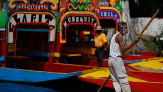 A gondolier poles one of the colorfully painted wooden boats known as trajineras at the Nuevo Nativitas dock at Xochimilco