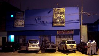 Police officers, wearing protective clothing, stand outside a disco in Lima, Peru, Sunday, Aug. 23