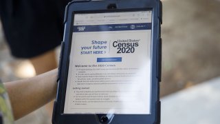 A YMCA youth ambassador holds a tablet with a Census 2020 interview questionnaire during a community food distribution in Los Angeles, Aug. 12, 2020.