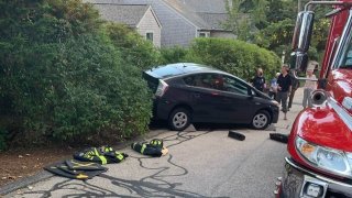 Officials say an 80-year-old woman's car backed over her, pinning her, in Falmouth, Massachusetts.