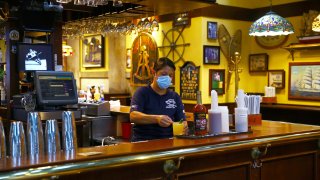 A bartender in Cheers finishes a drink order at Quincy Market in Boston on July 1, 2020.