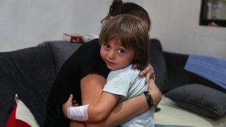 Hiba Achi hugs her son, three-year-old Abed Achi, at her house in Beirut, Lebanon, Tuesday, Aug. 11, 2020. Abed was playing with his Lego blocks when the huge blast ripped through Beirut, shattering the nearby glass doors.
