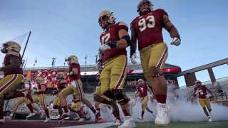 Boston College football players run onto the field at Alumni field