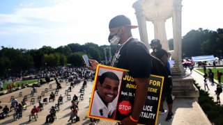 Sean Greene, brother of Ronald Greene, listens to speakers and holds sign reading “Justice for Ronald Greene” and “Stop Police Brutality” at the Lincoln Memorial during the March on Washington on August 28, 2020, in Washington, DC.