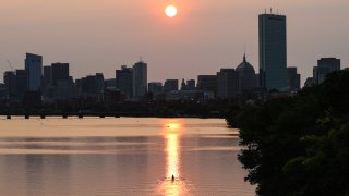 The Charles River, shot from the BU Bridge in Boston, is lit up by the smoky sun