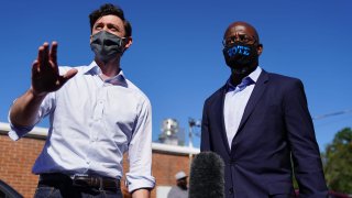 In this Oct. 3, 2020, file photo, Democratic U.S. Senate candidates Jon Ossoff and Rev. Raphael Warnock hand out lawn signs at a campaign event in Lithonia, Georgia.
