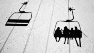 People on a Vermont ski lift are seen in silhouette in the snow