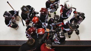 Youth hockey team gets a pep talk from coaches before heading into the third period.