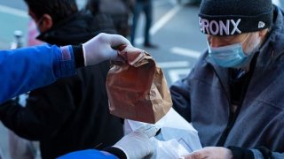 A man wearing a mask receives part of a hot meal at the Holy Apostles Soup Kitchen on December 15, 2020 in New York City.