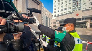 A policeman covers a camera to stop journalists from recording footage outside the Shanghai Pudong New District People's Court, where Chinese citizen journalist Zhang Zhan - who reported on Wuhan's COVID-19 outbreak and placed under detention since May - is set for trial in Shanghai on December 28, 2020.