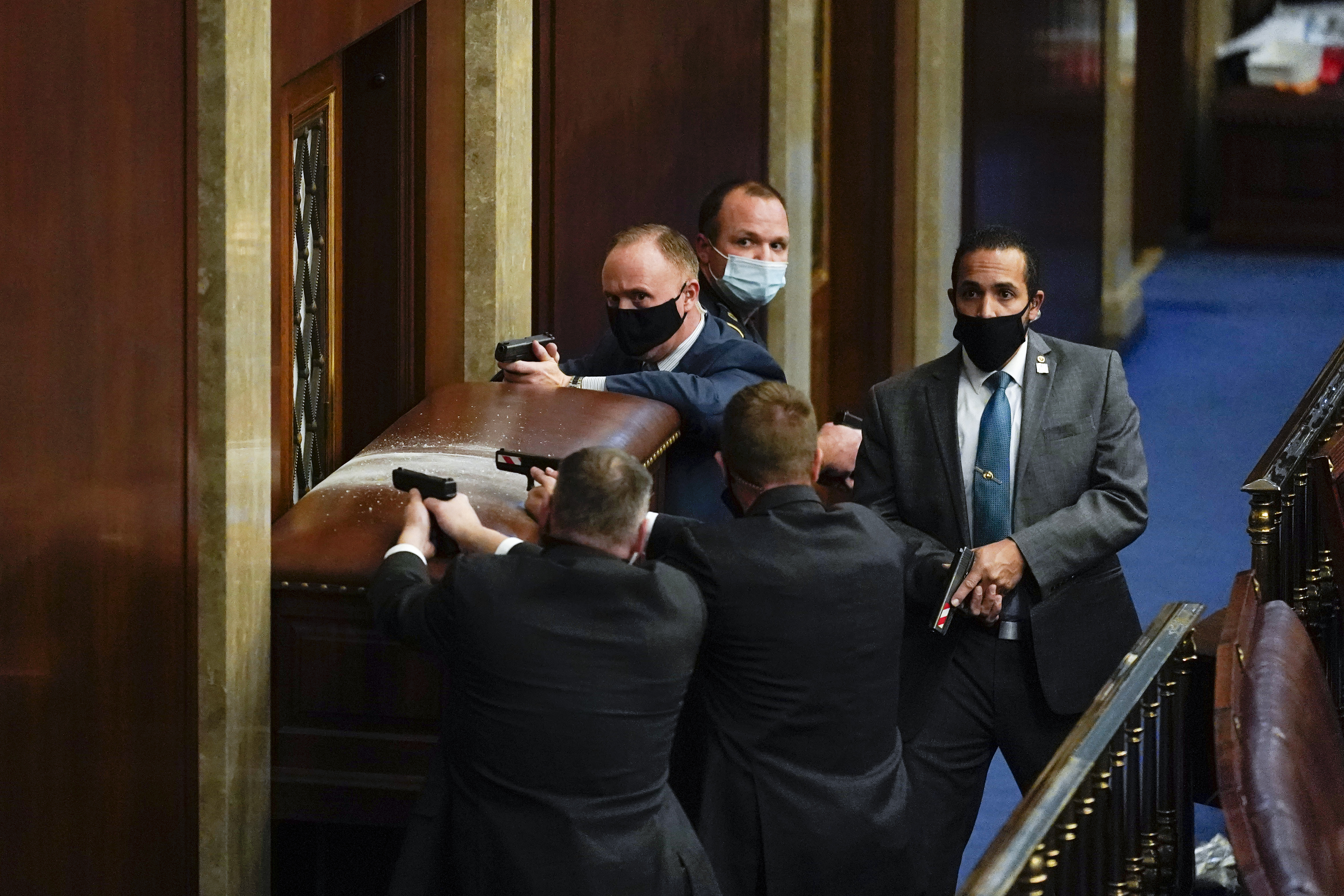 Capitol police stand with guns drawn near a barricaded door as protesters try to break into the House Chamber at the Capitol, Jan. 6, 2021, in Washington, DC.