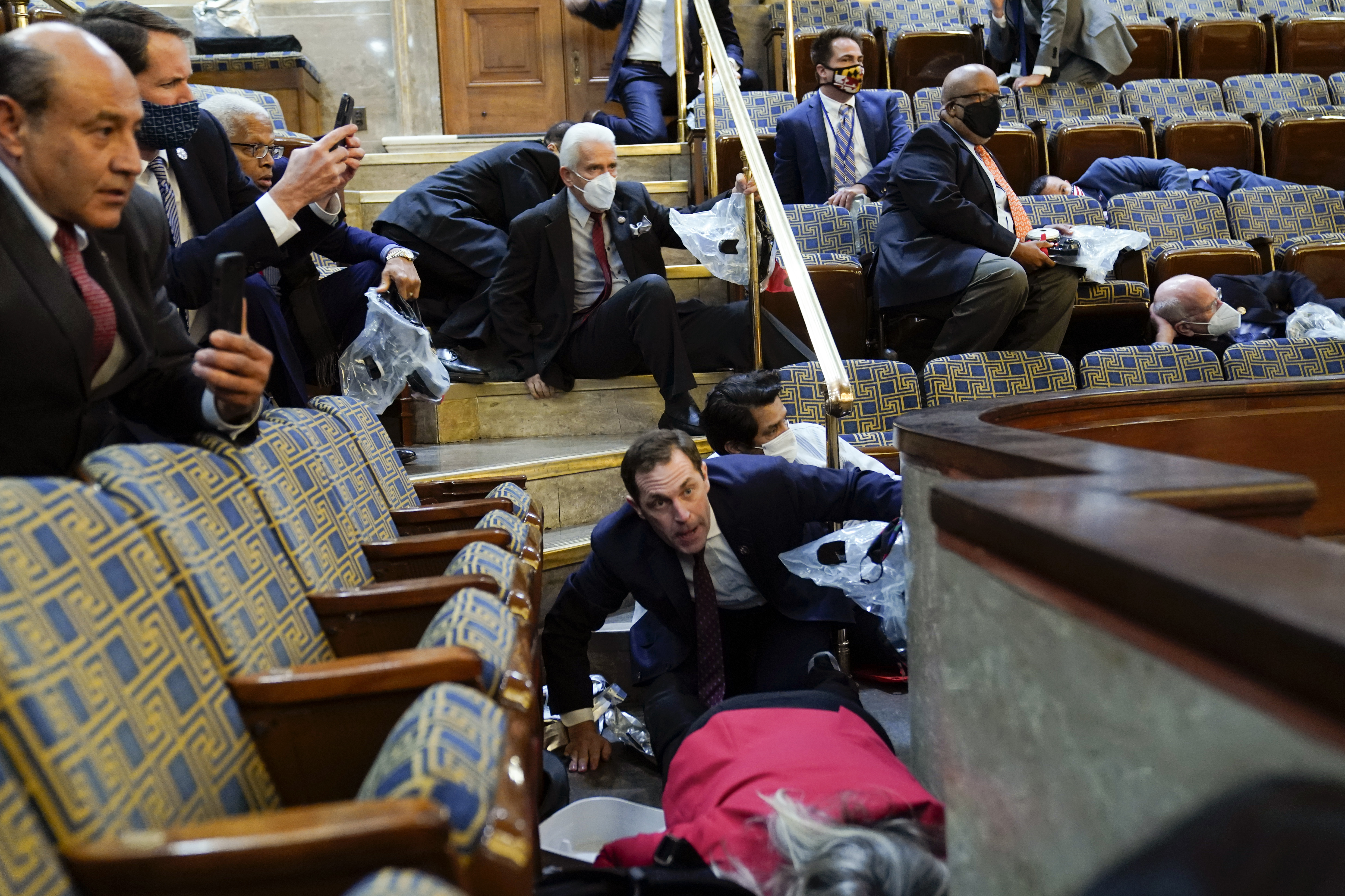 People shelter in the House gallery as protesters try to break into the House Chamber at the Capitol, Jan. 6, 2021, in Washington, DC.