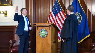 New Hampshire Gov. Chris Sununu holds his hand up as he is sworn in on Thursday, Jan. 7, 2021.
