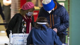 People check in to receive a dose of the Pfizer BioNtech Covid-19 vaccine at a mass vaccination site at Fenway Park in Boston, Massachusetts, U.S., on Friday, Jan. 29, 2021. In addition to 20,000 vaccination appointments that went live at Gillette Stadium and Fenway Park on Thursday morning, Govenor Baker said 15,000 more appointments had been made available at the Springfield and Danvers sites, which were “being booked.” Photographer: Adam Glanzman/Bloomberg via Getty Images