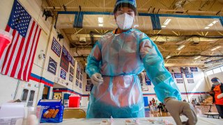 Elvin Toro, 26, a former army medic, organizes his syringes before giving out the next doses to a local resident at Central Falls High School in Central Falls, Rhode Island