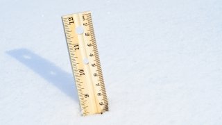 Wooden ruler stuck into snow bank to measure depth.
