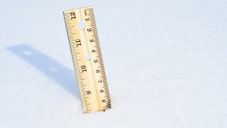 Wooden ruler stuck into snow bank to measure depth.