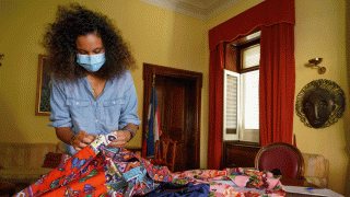 In this Aug. 13, 2020 file photo, fashion designer Stella Jean wears a face mask to curb he spread of COVID-19 as she holds fabrics during an interview with the Associated Press, in Rome.