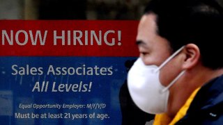 In this Dec. 1, 2020, file photo, a man walks past a "Now Hiring" sign in front of a store in Arlington, Virginia.