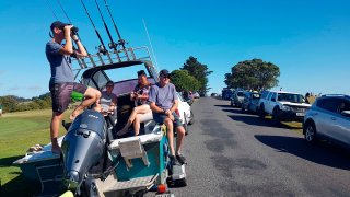 John Fitzgerald, left, on holidays with his wife Rita and friends, scans the horizon from high ground for any sign of a tsunami near Waitangi, New Zealand, Friday, March 5, 2021. A powerful magnitude 8.1 earthquake struck in the ocean off the coast of New Zealand prompting thousands of people to evacuate and triggering tsunami warnings across the South Pacific.