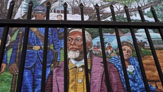 Past Amherst, Mass., area residents Henry Jackson, center, Lt. Frazar Stearns, left, and Anna Reed Goodwin, right, are featured on the Amherst Community History Mural, as seen through the adjacent West Cemetery fence, Friday, Jan. 15, 2021, in Amherst, Mass.