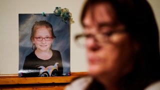 Patti Burt poses for a portrait near a photo of her granddaughter, 9-year-old Ava Lerario,