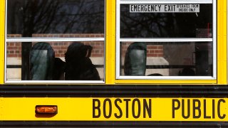 A student is silhouetted as she sits on the school bus